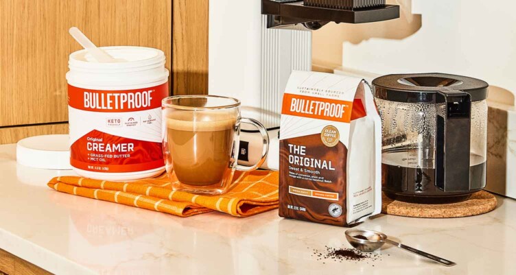 Tub of Bulletproof Creamer and Bulletproof Coffee grounds sitting on Counter with a prepared cup of coffee