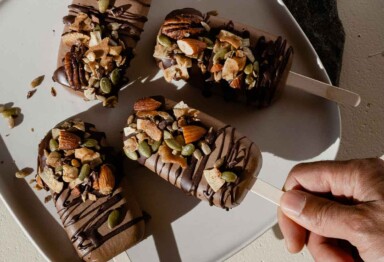 Hand grabbing Hazelnut keto fudgesicles from plate