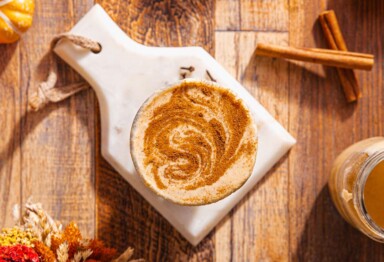 Overhead shot of Bulleproof Pumpkin Coffee with cinnamon sticks and seasonal fall decor.