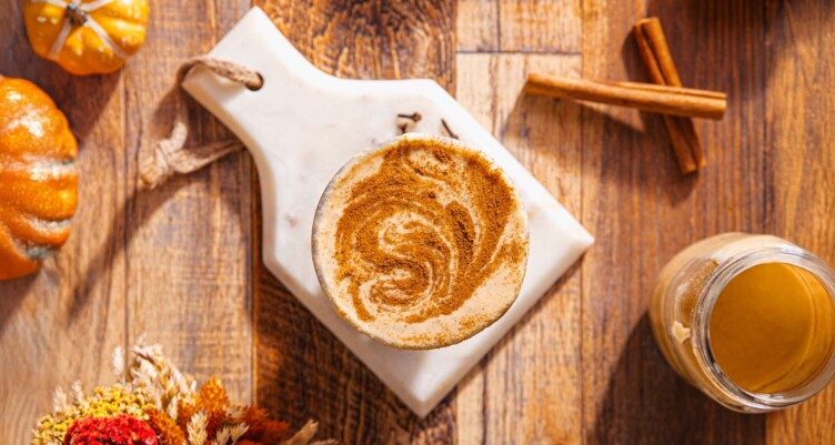 Overhead shot of Bulleproof Pumpkin Coffee with cinnamon sticks and seasonal fall decor.