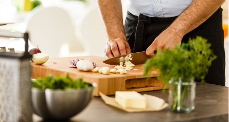 Man slicing garlic on cutting board.