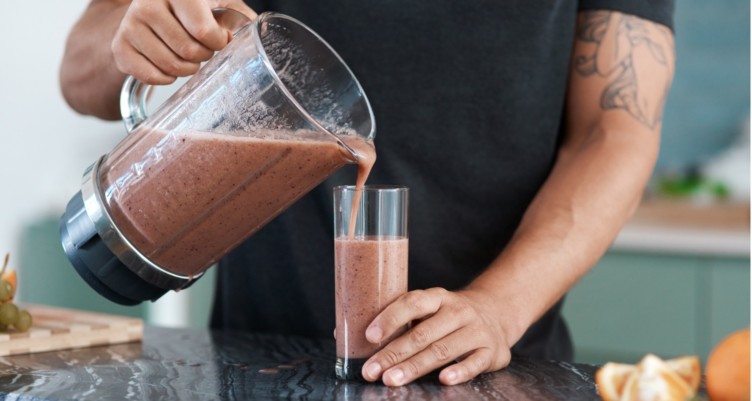 Man pouring smoothie into a glass.