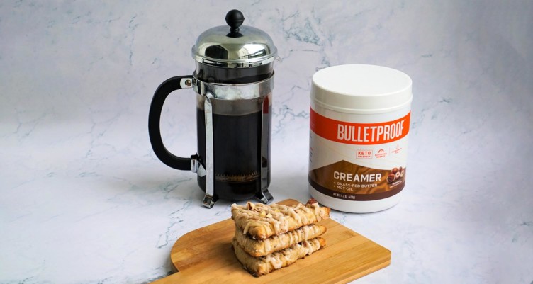 scones next to a french press filled with hot coffee and a canister of Bulletproof hazelnut creamer