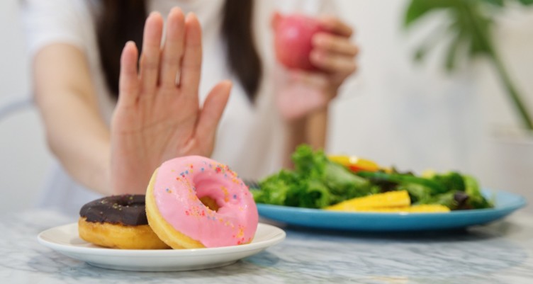 A hand gesturing against a plate of donuts