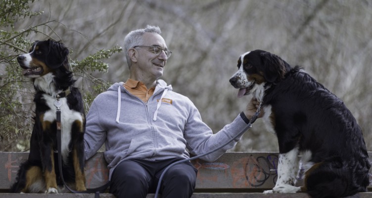 Bulletproof CEO Larry Bodner sitting on a bench in the woods with his two dogs