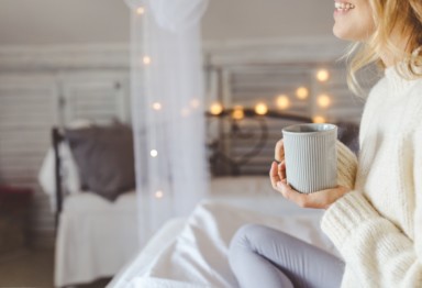 Woman holding a mug in room decorated for holidays.