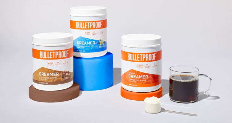 All three Bulletproof Creamer tubs next to a cup of coffee