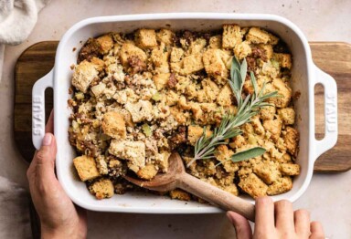 Hand scooping Bulletproof Keto Stuffing out of a casserole dish
