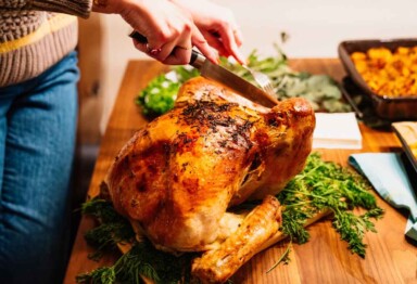 Hand cutting into Thanksgiving dinner turkey roast