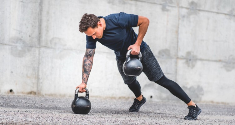 Man doing kettlebell plank row exercise.