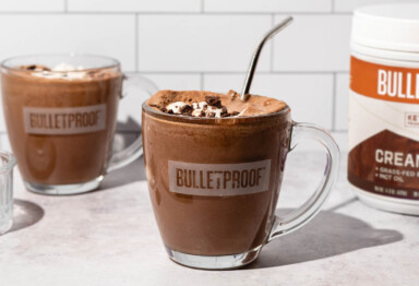 A Bulletproof mug filled with keto frozen hot chocolate next to a Mocha Creamer tub
