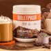 Bulletproof Mocha Creamer tub sitting next to coffee drink and a pile of chocolate chunks and coffee beans