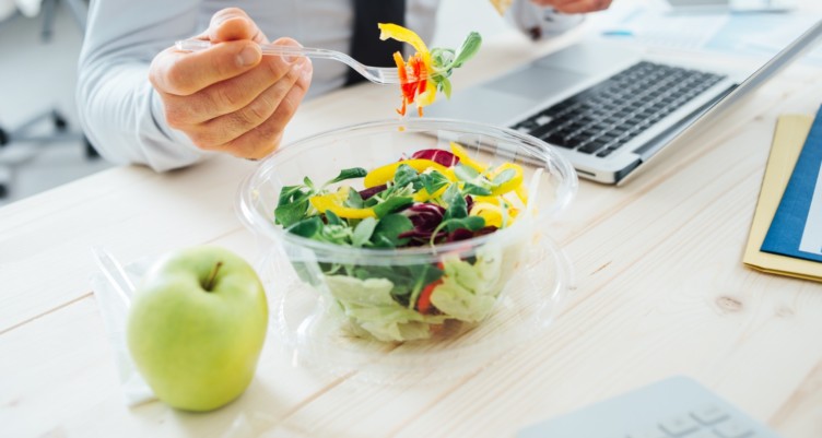 Businessman eating a salad at work.