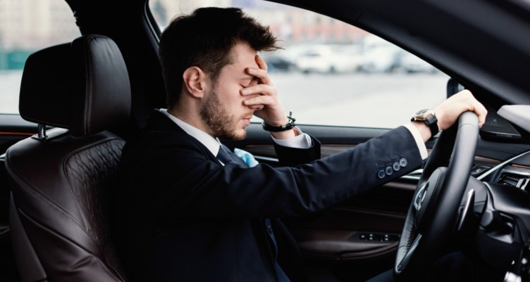 Stressed man holding his face while sitting in a car.