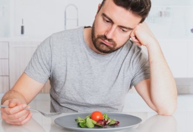 Sad-looking man eating a salad.