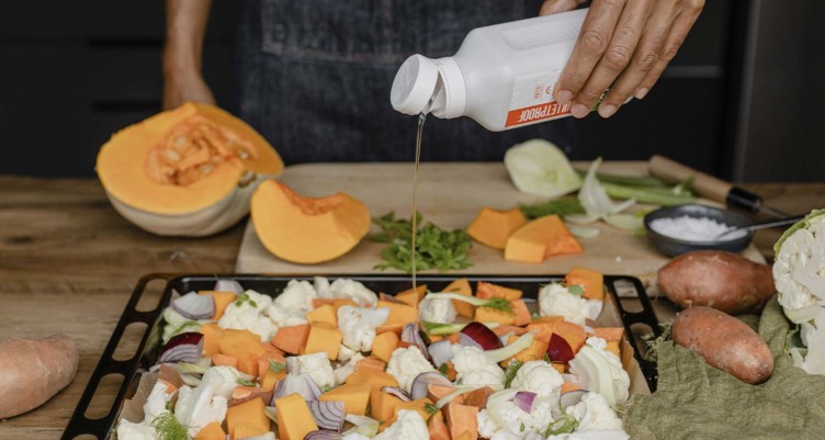 Pouring Bulletproof MCT Oil over chopped veggies before roasting.