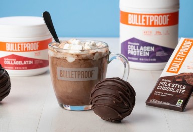 A mug of hot chocolate next to hot chocolate bombs and Bulletproof products