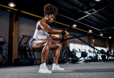 Athletic woman doing full-body workout with ropes.