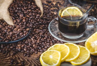 Coffee cup and roasted coffee beans with lemon slices.
