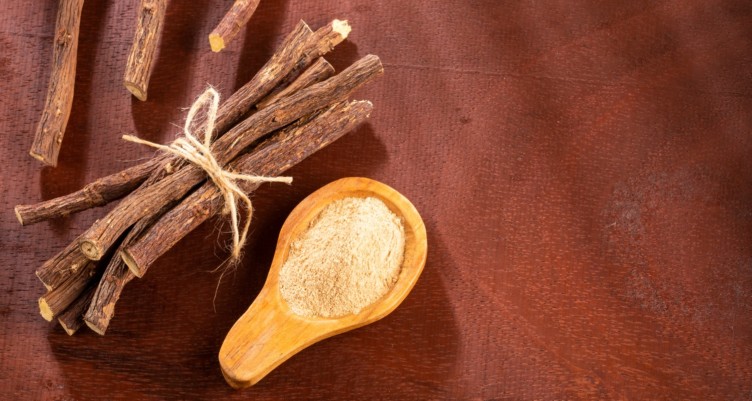 A spoonful of licorice powder next to licorice roots.