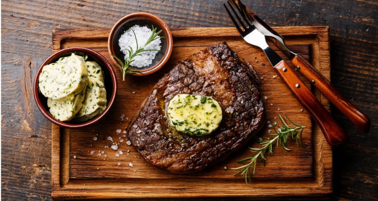 Ribeye steak with butter on cutting board