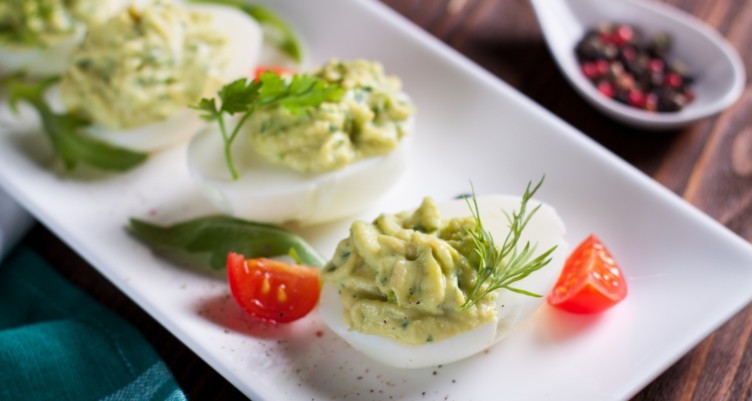 Deviled eggs with avocado on plate