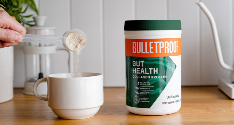 Adding a scoop of Bulletproof Gut Health Collagen Protein to a cup of coffee.