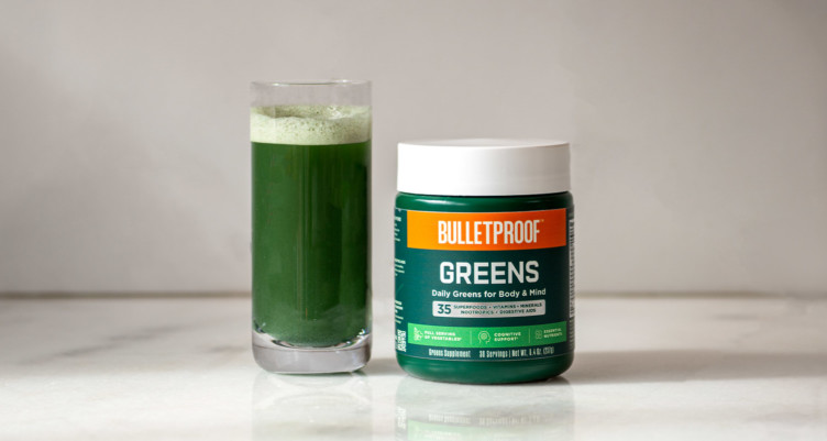 A glass of Bulletproof Greens next to container.