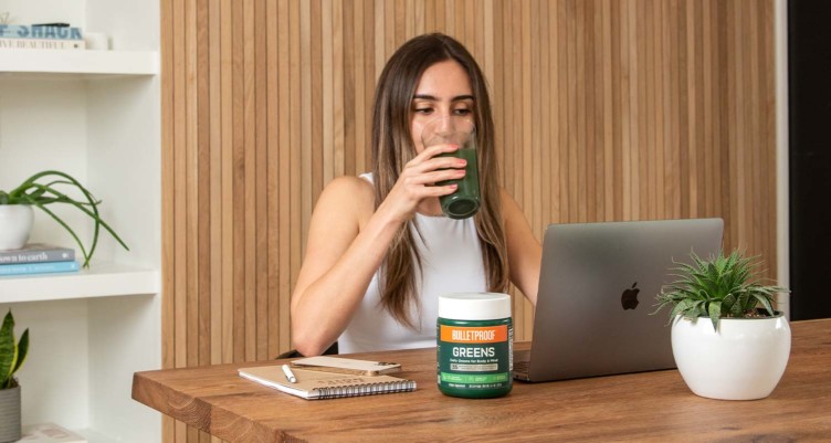 Woman drinking Bulletproof Greens while working on laptop.