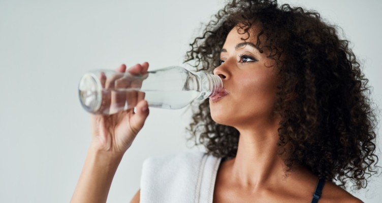 Woman drinking bottle of water after workout.
