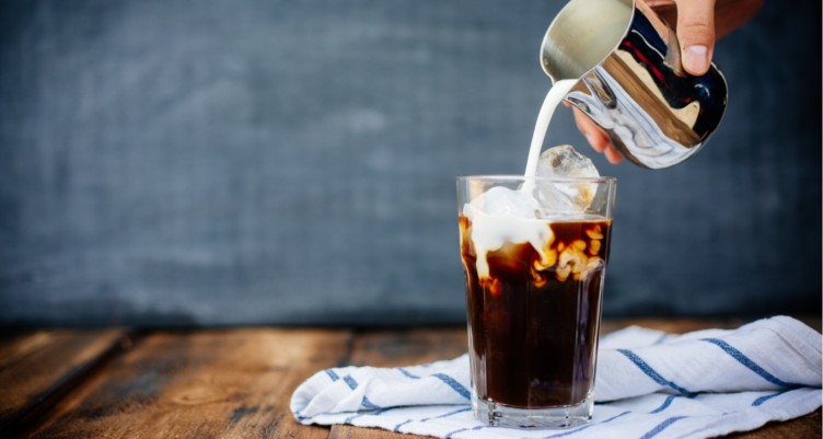 Preparing iced latte with cream.