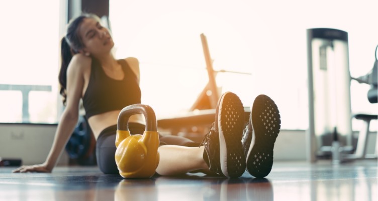 Woman sitting down at gym after doing kettlebell workout.