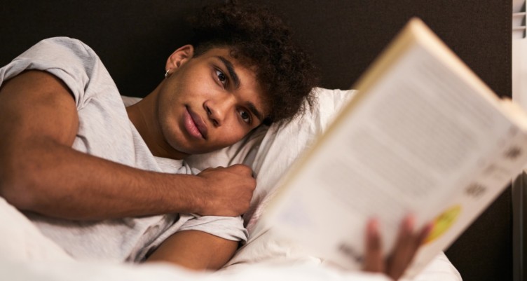 Man reading a book in bed at night