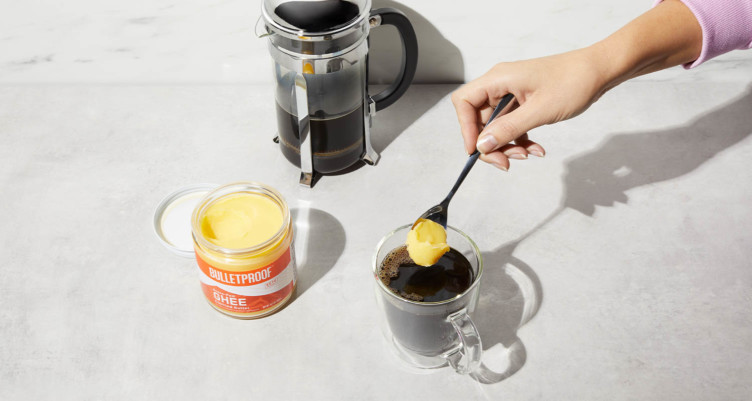 Putting scoop of Bulletproof Grass-Fed Ghee into a cup of coffee