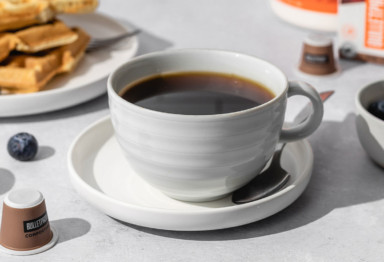 Cup of coffee with waffles and Bulletproof coffee pods.