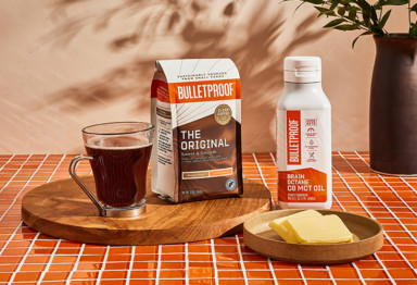 Bulletproof The Original coffee, Brain Octane Oil and butter on countertop by cup of black coffee