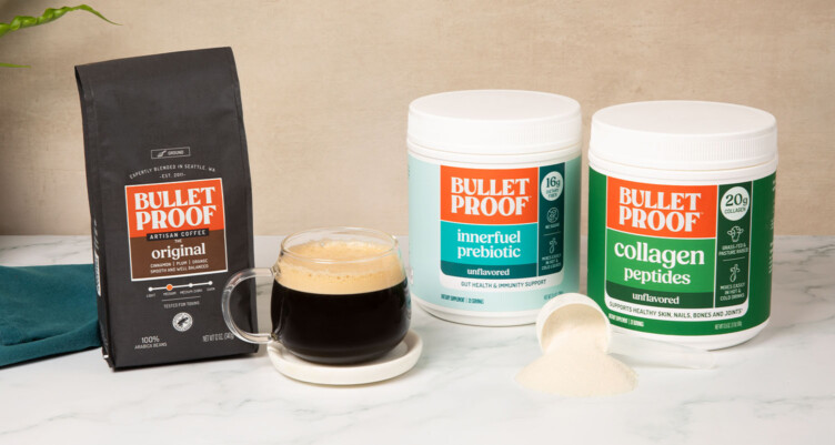 Bulletproof Original Ground Coffee bag, tub of Innerfuel Prebiotic, tub of Unflavored Collagen Peptides sitting next to coffee mug on counter with scoop of collagen powder.