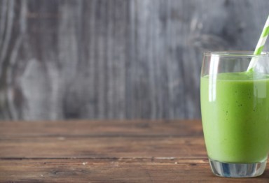 A kale shake with a straw on a wooden counter