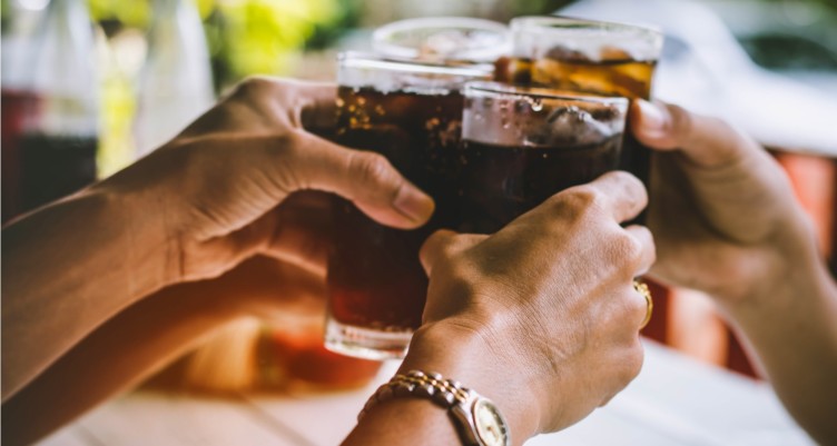 People toasting with glasses of soda.