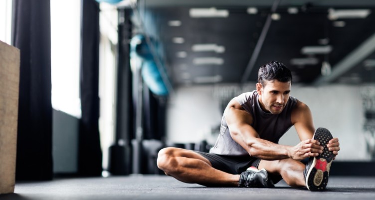 Man doing leg stretches in the gym.