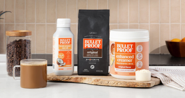 Bulletproof The Original coffee, Brain Octane Oil and Bulletproof Original Creamer on countertop with a mug of creamy coffee.