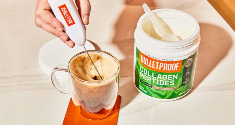 Hand using Bulletproof branded frother, frothing a creamy cup of Bulletproof coffee next to Bulletproof Collagen Peptides