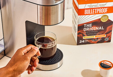 hand reaching for a cup of coffee that was brewed from a original bulletproof pod