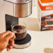 hand reaching for a cup of coffee that was brewed from a original bulletproof pod