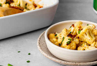 a pan of loaded cauliflower casserole next to a bowl of loaded cauliflower casserole