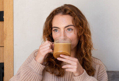 Woman with curly red hair siping on Bulletproof coffee