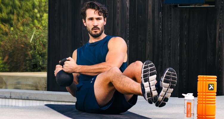 Man on a yoga mat whilst lifting a dumbell