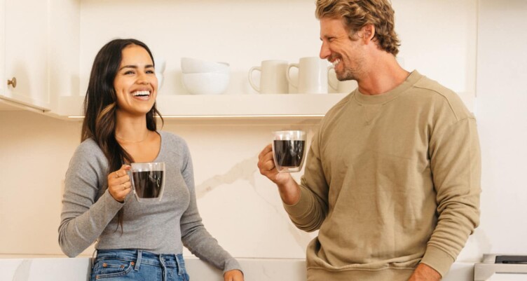 Man and woman standing  holding cups of coffee and smiling