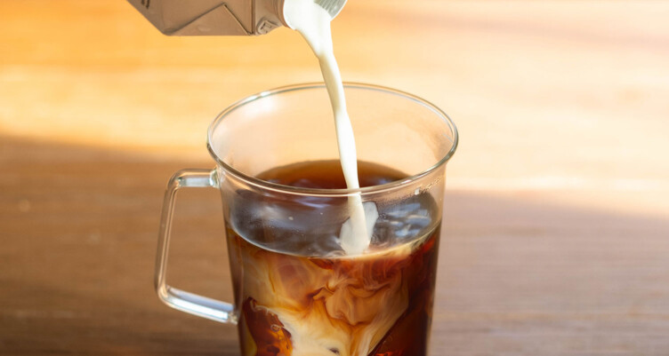 Milk being poured into an iced coffee 