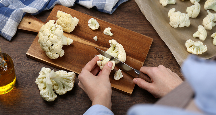 hands cutting up raw cauliflower